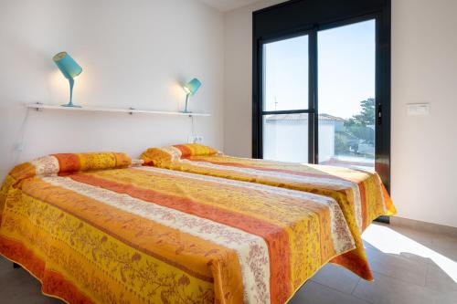 sypialnia z 2 łóżkami z pomarańczowymi i żółtymi kocami w obiekcie AT033 La Siesta w mieście Torredembarra