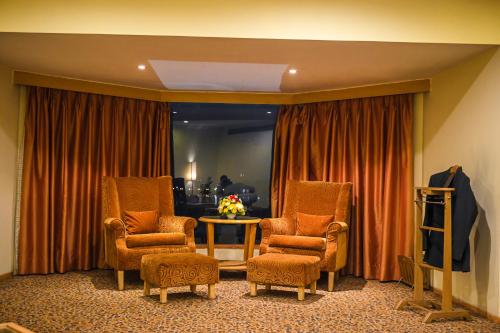 a room with two chairs and a table and a television at Katriya Hotel and Tower in Hyderabad