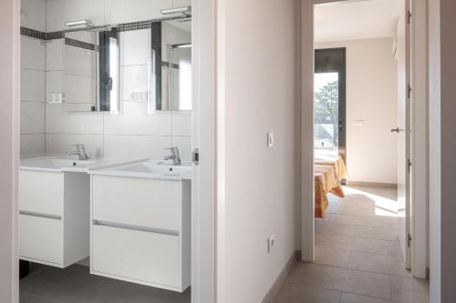 a white bathroom with two sinks and a mirror at AT033 Bonita villa con piscina privada, completamente equipada in Torredembarra