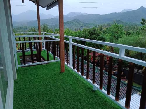 a balcony with green grass and mountains in the background at Menjangan View in Banyuwedang