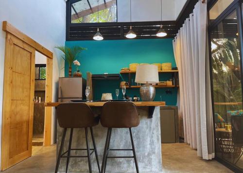uma cozinha com um bar com dois bancos e uma parede verde em Casita Vinita em Nosara