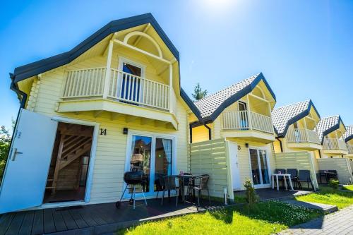 a yellow house with a deck and patio at Perłowe Wzgórze in Ustronie Morskie