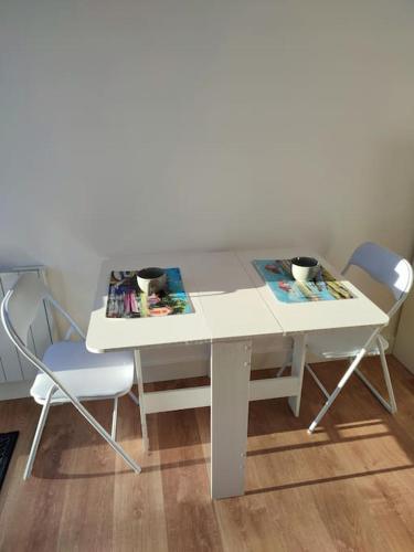 uma mesa branca e cadeiras com duas chávenas em Le petit chalet d'Audenge em Audenge