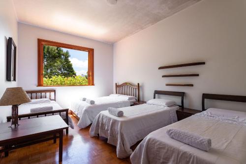 um quarto com três camas e uma janela em Aconchegante Sítio na Serra com piscina em Itaipava 26 hóspedes em Itaipava