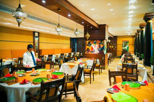 a man standing in a dining room with tables at Katriya Hotel and Tower in Hyderabad