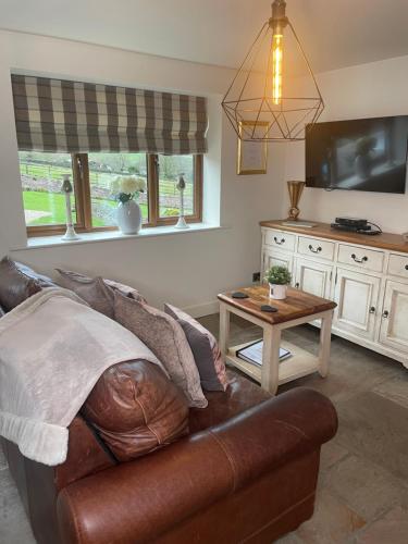 a living room with a leather couch and a table at Hollies Cottage in Keighley