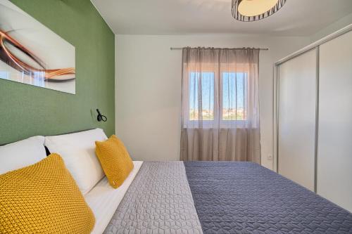 a bedroom with a bed with yellow pillows and a window at Mare‘s Place - Premium Seaview Apartment in Slatine