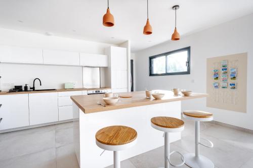 une cuisine avec des placards blancs et un îlot en bois avec des tabourets dans l'établissement La Perle Villa neuve, proche gare, comédie, et tramway, à Montpellier