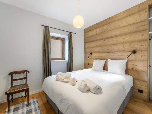 ein Schlafzimmer mit einem großen weißen Bett und einer Holzwand in der Unterkunft Chalet familial neuf avec sauna et spa, proche des pistes, accueille 12 personnes et animaux admis - FR-1-570-30 in Praranger