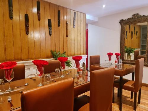 ein Esszimmer mit Tischen, Stühlen und roten Rosen in der Unterkunft Le Cocooning 974 Hôtel Restaurant Réunion in Antananarivo