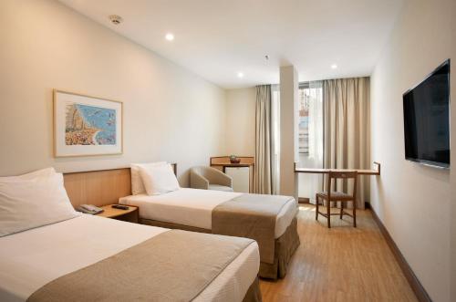 um quarto de hotel com duas camas e uma televisão de ecrã plano em Windsor Plaza Copacabana no Rio de Janeiro