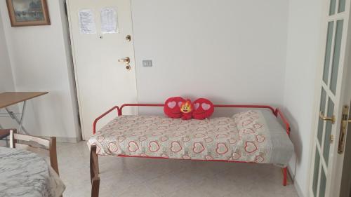 a red teddy bear sitting on top of a bed at Apolloni di Loano appartamento privato - Codici Citra visibili su STRUTTURA in Loano