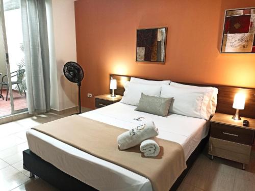 a bedroom with a large bed with two lamps and a fan at Laureles Guest House LGH Hotel in Medellín