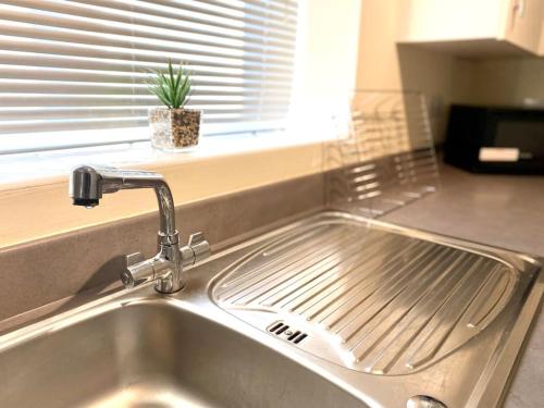 a kitchen sink with a faucet next to a window at Amazing 2-Bed City Centre Apt with Parking in Spon End