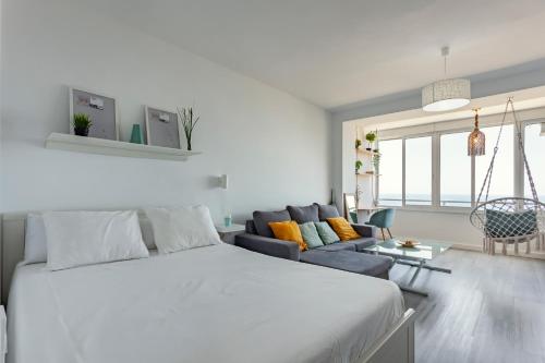 Un dormitorio blanco con una cama y un sofá. en Estudio con increíbles vistas a la Playa + Piscina, en Aguadulce
