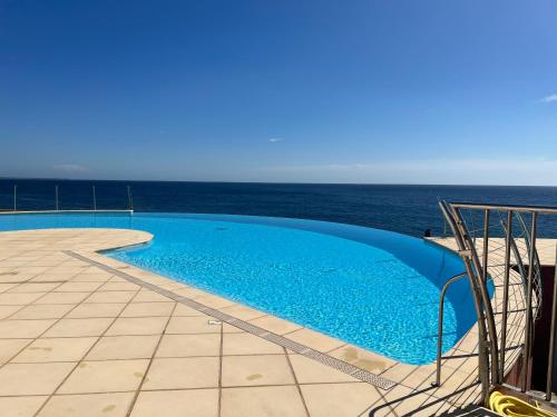 une piscine avec l'océan en arrière-plan dans l'établissement Appartement dans résidence pieds dans l’eau, au Trayas