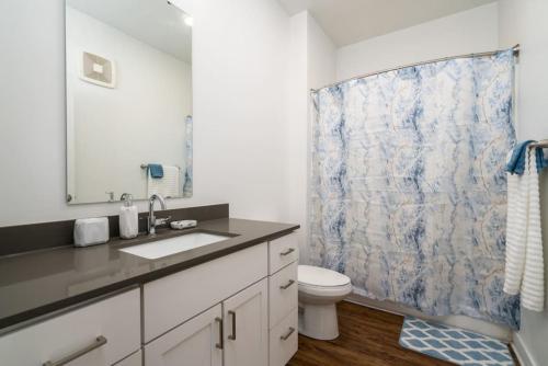 baño con lavabo y aseo con cortina de ducha en Cozy 2-Bedroom Fountain Square Indy, en Indianápolis