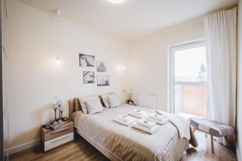 a white bedroom with a large bed and a window at Apartament Niko in Toruń