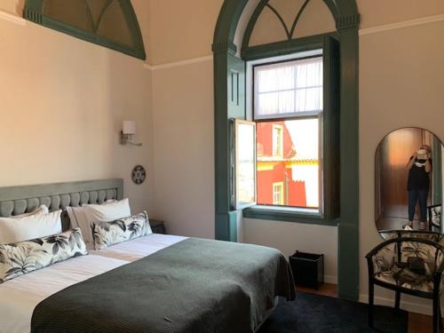 a bedroom with a large bed and a window at Ilha 12 Suites in Coimbra
