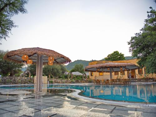 a resort with a swimming pool with an umbrella at Wild Rose Resort and Spa in Pushkar