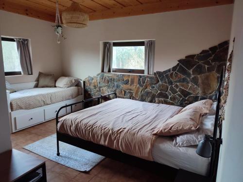 1 dormitorio con cama y pared de piedra en Alojamento Casa do Cabeço Alombada, en Macinhata do Vouga