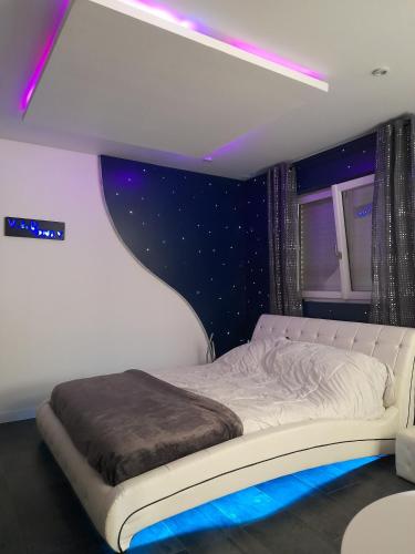 a bedroom with a white bed with purple lights at Chambres 2 caps in Ambleteuse