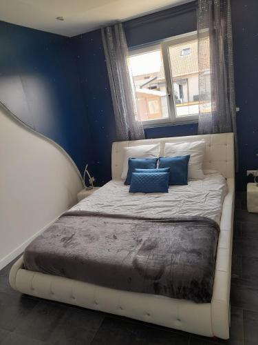 a bedroom with a white bed with blue pillows at Chambres 2 caps in Ambleteuse