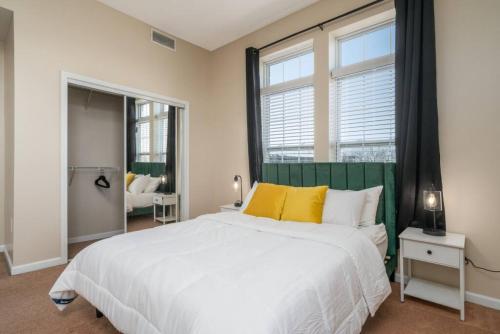1 dormitorio con 1 cama blanca grande con almohadas amarillas en Downtown INDY Private Bedroom - Shared, en Indianápolis