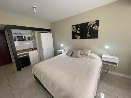 1 dormitorio con 1 cama blanca y cocina en Hermoso departamento minimalista en Buenos Aires