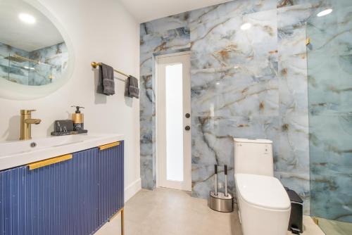 TamiamiにあるDeluxe house heated pool L08の白いトイレと大理石の壁が備わるバスルーム