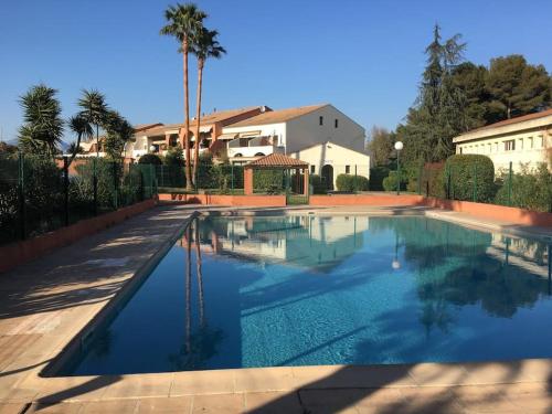 une piscine avec de l'eau bleue dans une cour dans l'établissement LA CALMERAIE, à Villeneuve-Loubet