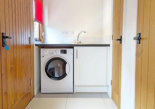 uma cozinha com uma máquina de lavar roupa e um lavatório em Old Root House, Lavant em Chichester