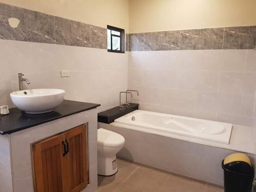 a bathroom with a sink and a tub and a toilet at The old normal private residences in Panglao