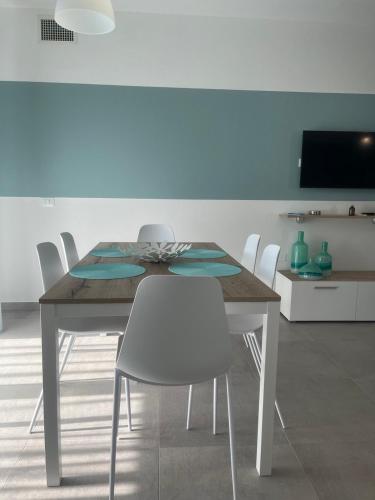 a dining room with a table and white chairs at "La Terrazza di Via Roma" Delta del Po - Private Parking in Porto Viro
