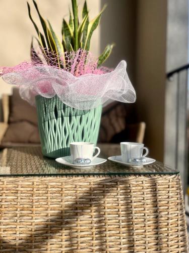 a table with two cups and a vase with flowers at "La Terrazza di Via Roma" Delta del Po - Private Parking in Porto Viro