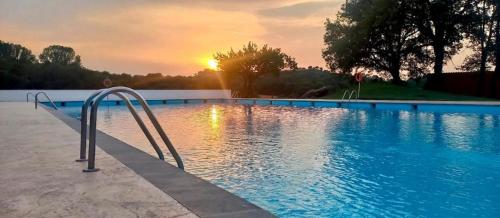 una piscina con un pasamanos de metal frente a la puesta de sol en El Nou Roquet, en Tavernoles