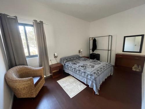 a bedroom with a bed and a chair and a window at Tia Nita Apartamentos in Mindelo