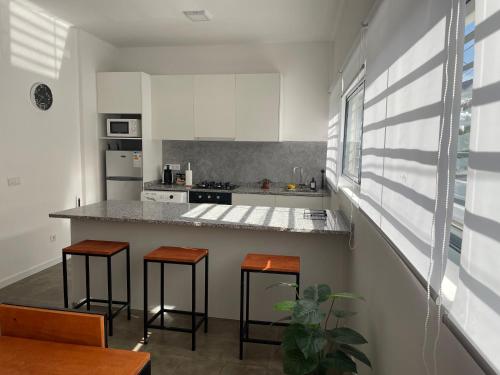 a kitchen with white cabinets and a counter with stools at Tia Nita Apartamentos in Mindelo