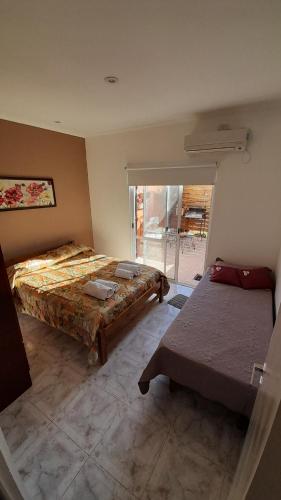 a bedroom with two beds and a sliding glass door at CASA VERDE 1 depto in Carhué
