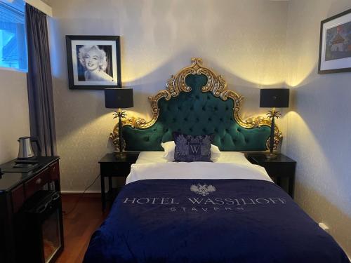 a bedroom with a bed with a green headboard at Hotel Wassilioff - Unike Hoteller in Stavern