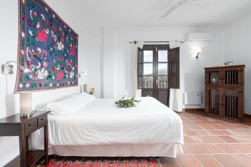a bedroom with a white bed and a painting on the wall at Cerro de Hijar in Tolox