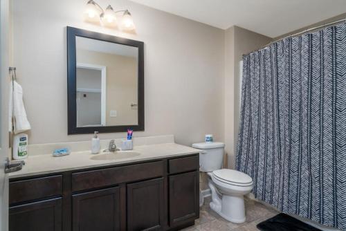 a bathroom with a sink and a toilet and a mirror at Lovely 3BD 3BA Downtown Indy in Indianapolis