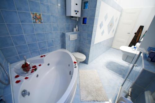 a blue tiled bathroom with a tub and a toilet at Phoenix Apartment in Budapest