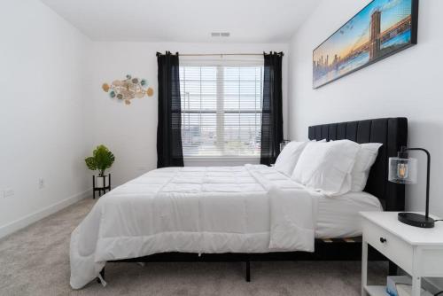 a white bedroom with a large bed and a window at Luxurious 2 Bedroom in Morton Groove in Morton Grove