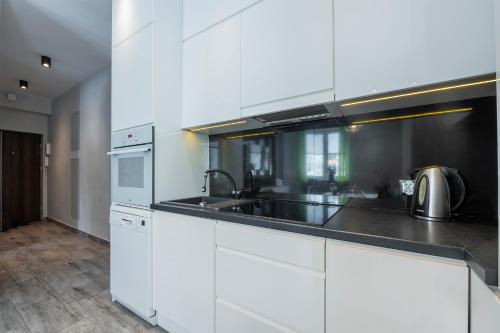 kuchnia z białymi szafkami, zlewem i urządzeniami w obiekcie HILLWOOD Apartment w Łodzi