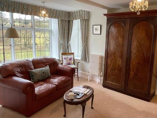 a living room with a brown leather couch and a table at Edgcott House in Exford
