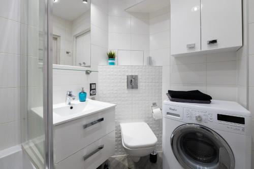 a white bathroom with a washing machine and a sink at HILLWOOD Apartment in Łódź