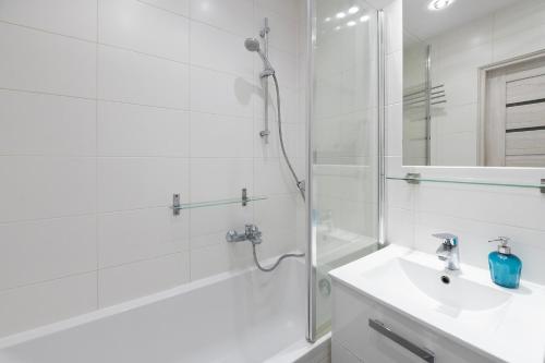 a white bathroom with a shower and a sink at HILLWOOD Apartment in Łódź