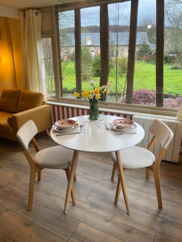 une table blanche et des chaises dans une pièce avec une fenêtre dans l'établissement Gîte « le Moulin » à 2 pas de la mer, à Saint-Martin-le-Gaillard