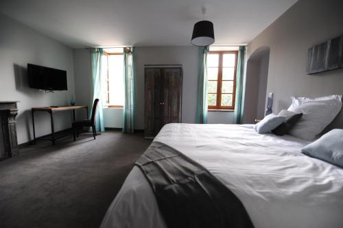 a bedroom with a large white bed and a desk at Logis Hôtel Château De Palaja in Carcassonne